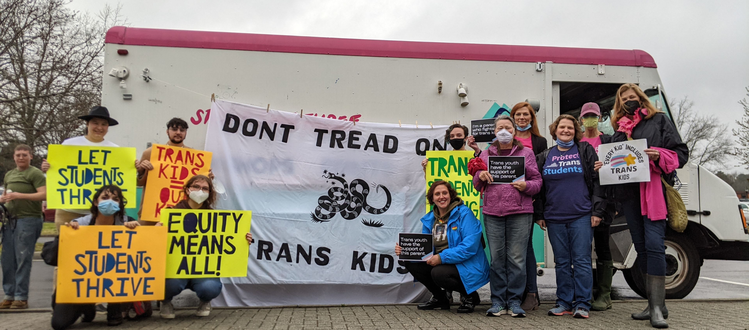 a group of parents and community advocates standing in front of Studio Two Three truck with a banner in the center that reads "Don't Tread on Trans Kids". Community members held pro-trans rights signs like "Let students thrive" and "Trans kids are our kid
