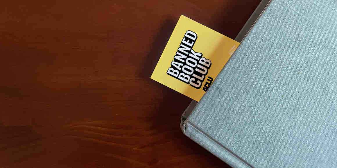 photo of a book mark sticking out from a light blue cover book. The bookmark reads "Banned Books Club"