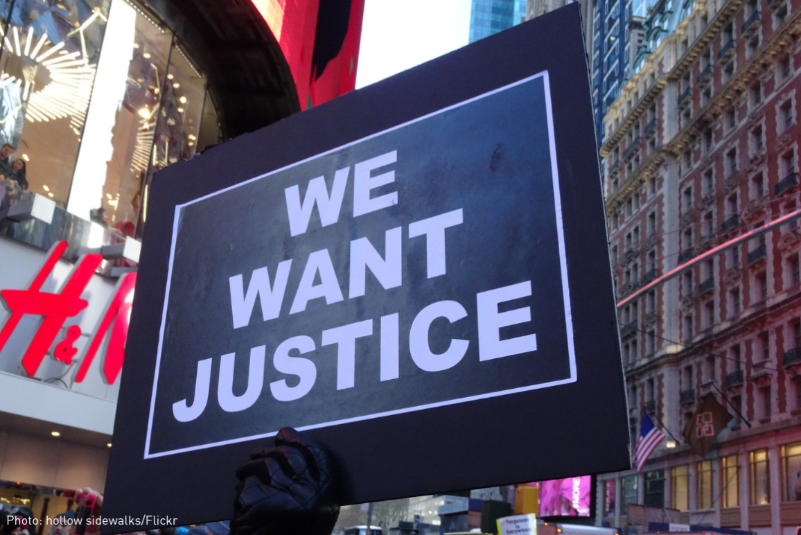 a protest sign that says "We Want Justice"