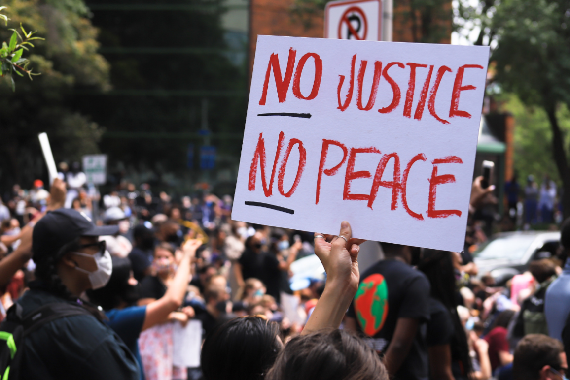 a white protest sign with the text in red "No Justice No Peace"