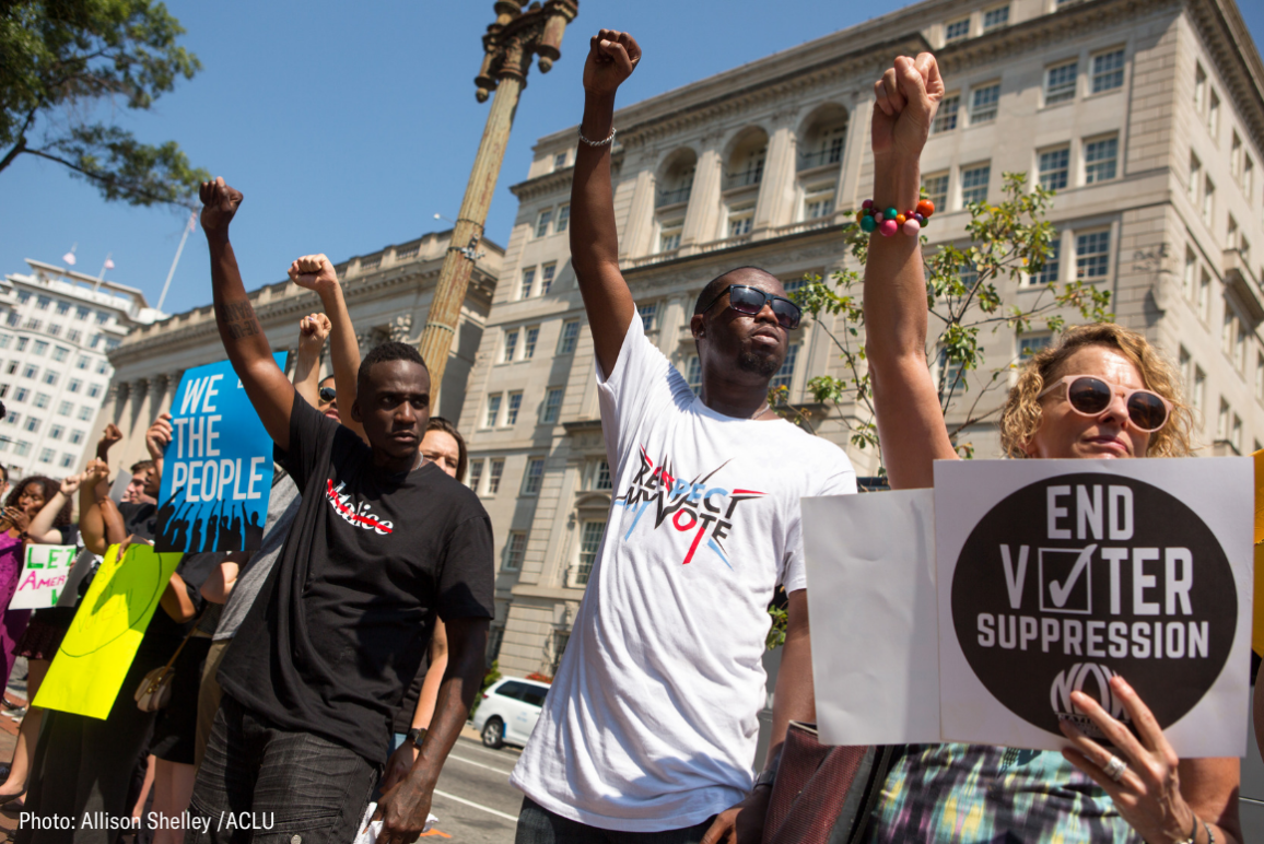 protesters holding signs that say "End Voter Suppression" and "Respect my Vote"