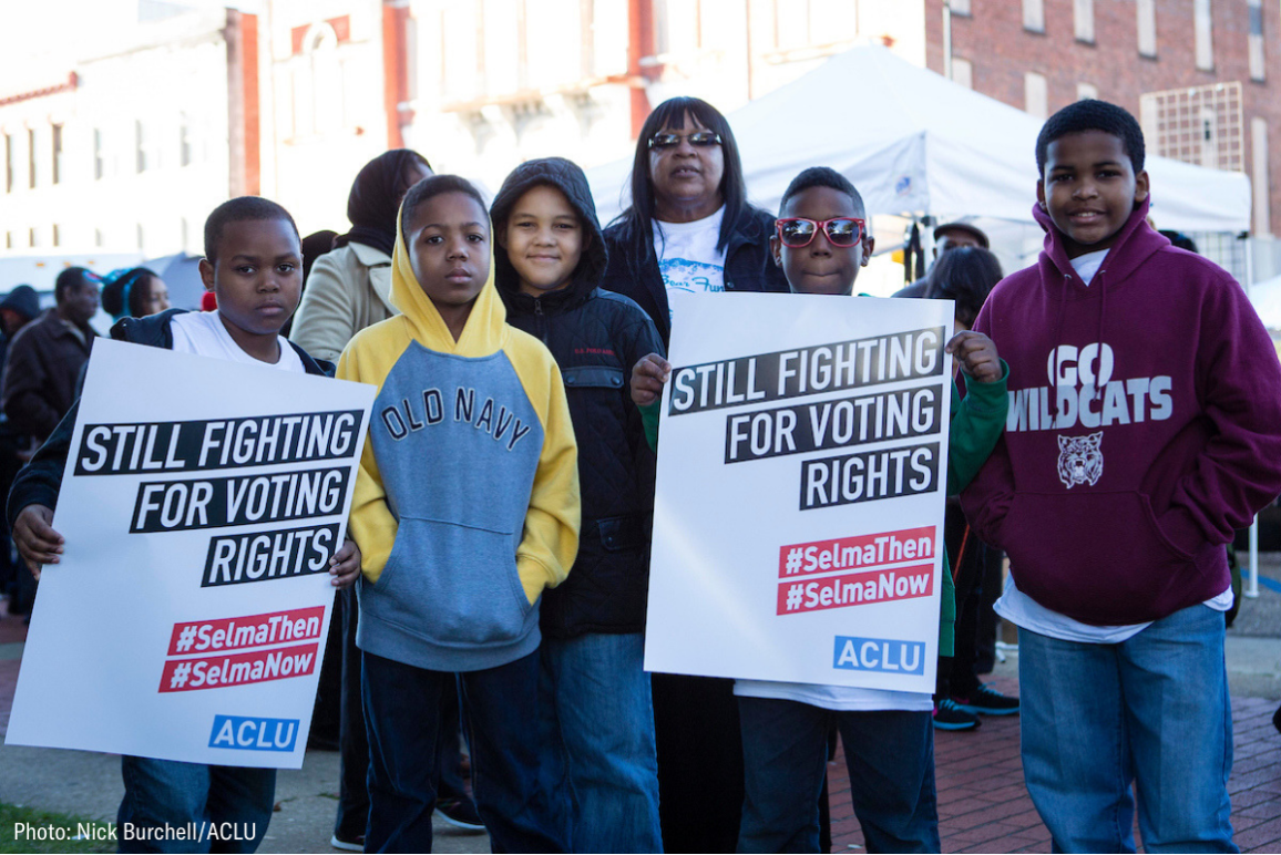 A group of black youths holding signs that say "still fighting for voting rights"
