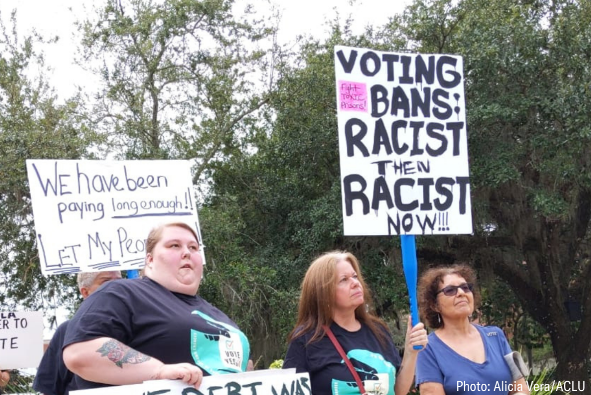 protesters holding a sign that says "voting bans: racist then, racist now"