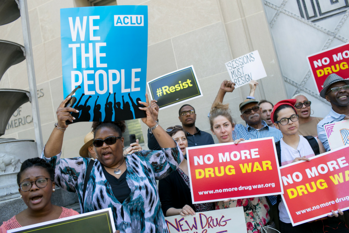 People holding signs that say "No More Drug War" and "We The People"
