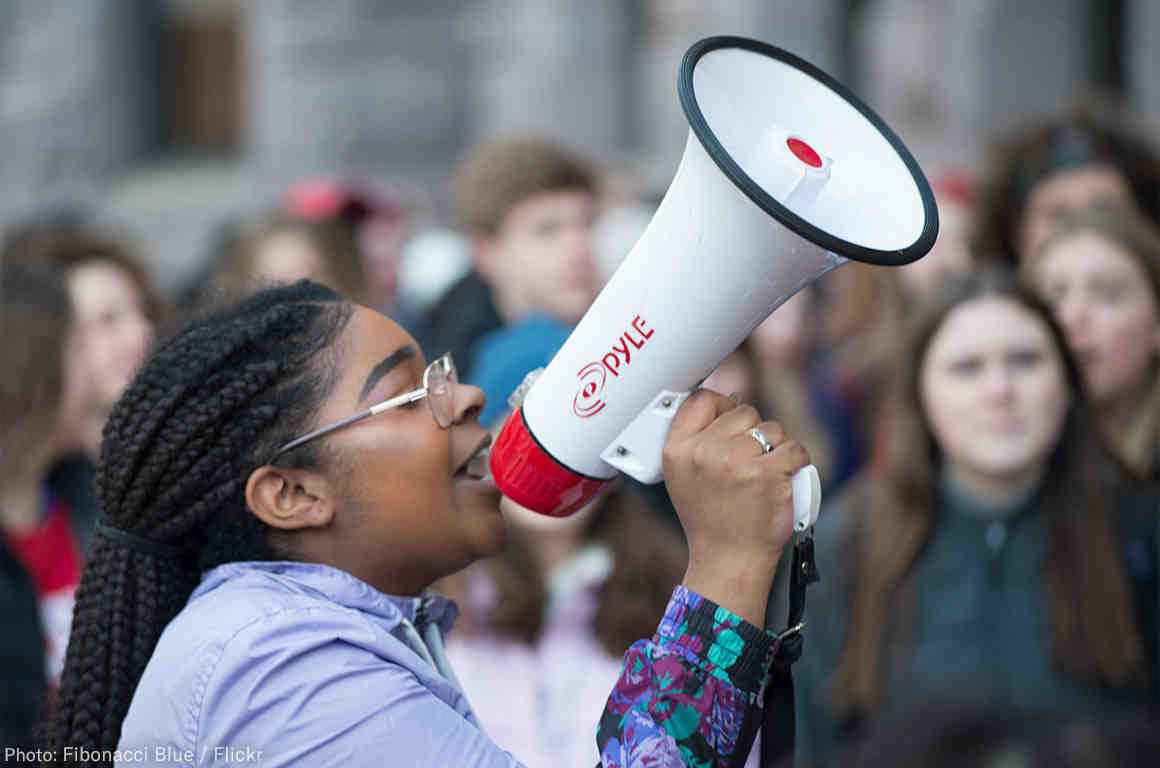 A student holding a speaker while attending a protest