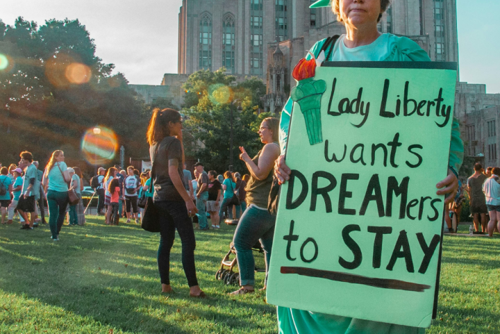 a protester dressed as Lady Liberty with a sign "Lady Liberty Wants Dreamers to Stay."