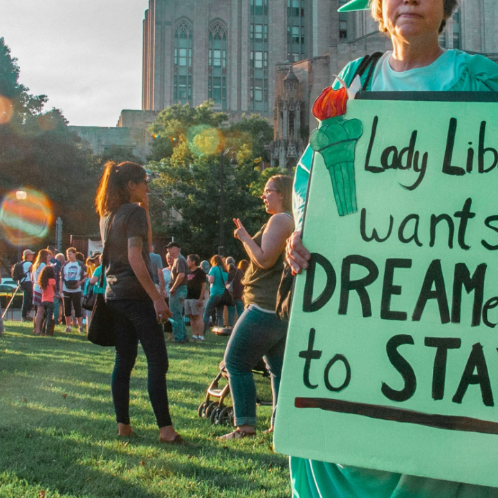 a protester dressed as Lady Liberty with a sign "Lady Liberty Wants Dreamers to Stay."