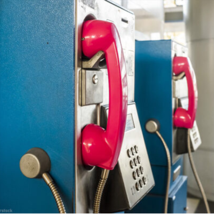 pay phone booths in prison with red phone over blue booth.