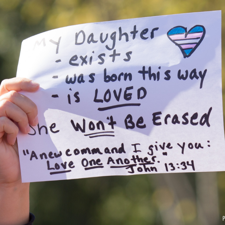 a protest sign with the message: My daughter exists, was born this way, is LOVED. She won't be erased.