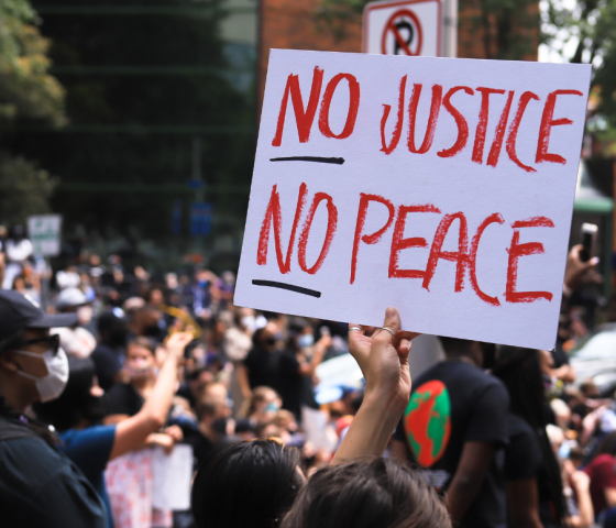 a white protest sign with the text in red "No Justice No Peace"