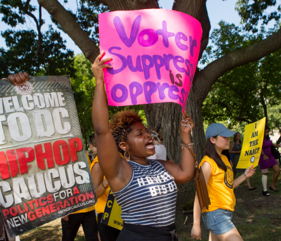 A black protester holding a sign that said voter suppression is oprression