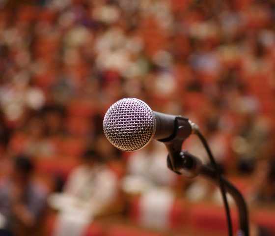 A mic in the foreground with audience in the background